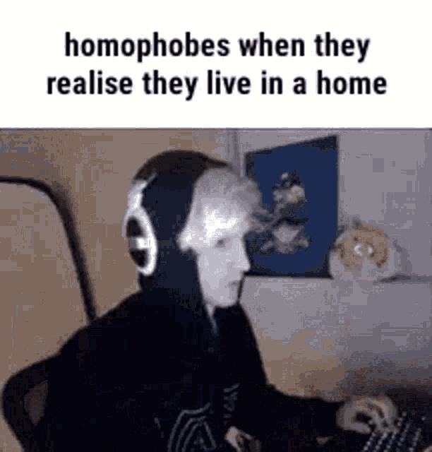 a person wearing headphones is playing a video game while sitting at a desk .