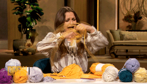 a woman is sitting at a table with balls of yarn in front of her