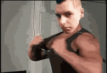 a young man with a mohawk is taking a selfie with his shirt off .