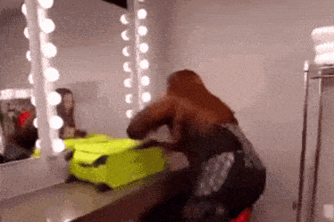 a woman is looking at herself in a mirror while holding a neon green suitcase