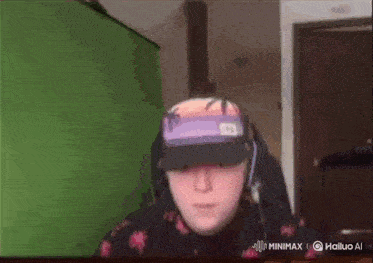 a man wearing a hat and headphones is sitting in front of a green screen ..