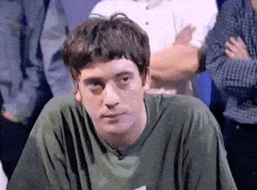 a man in a green shirt is looking at the camera with his arms crossed
