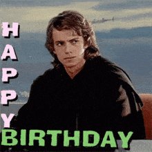 a man in a black jacket is sitting in front of a sign that says happy birthday .