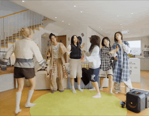a group of young women are dancing in a room with a speaker in the foreground