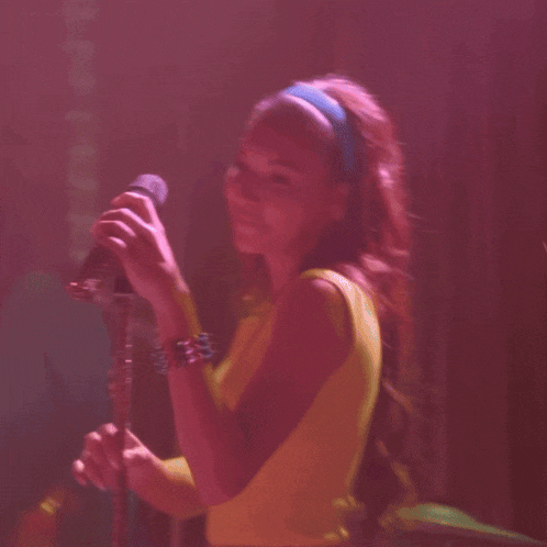 a woman singing into a microphone with a blue headband