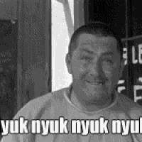 a man in a sweater is smiling in a black and white photo with the words yuk nyuk nyuk nyuk .