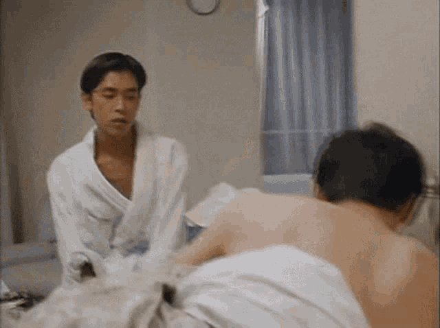 a man in a bathrobe is standing next to another man in a bathrobe