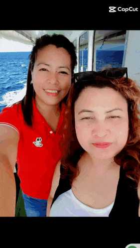 two women are posing for a picture and one has a red shirt with a cat on it