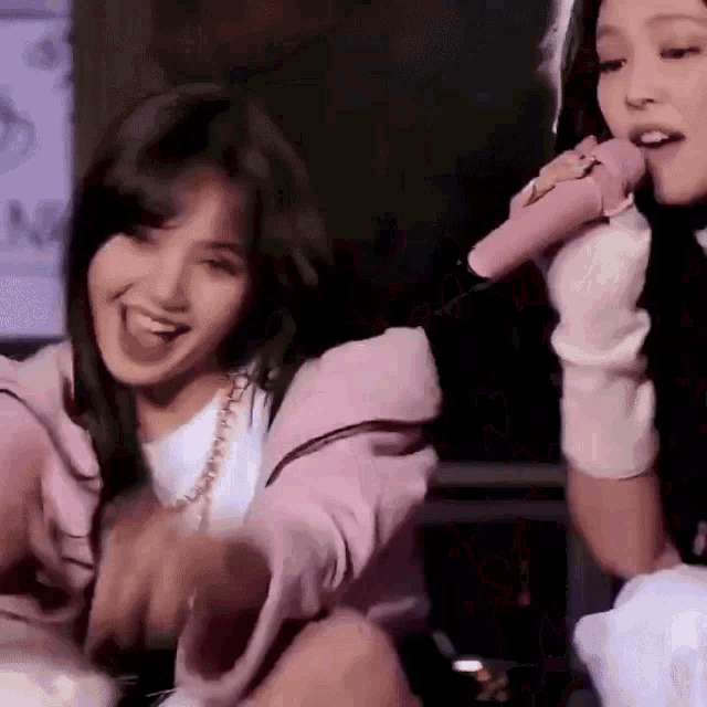 two women are singing into microphones while sitting next to each other in a room .