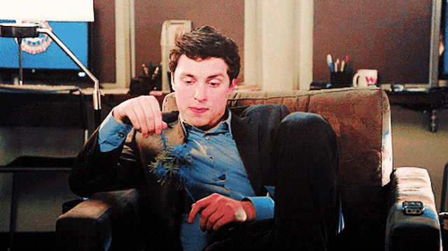 a man in a suit sits on a couch with his feet crossed