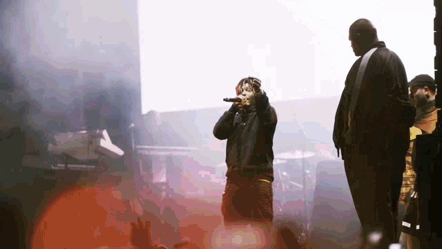 a man singing into a microphone while another man watches