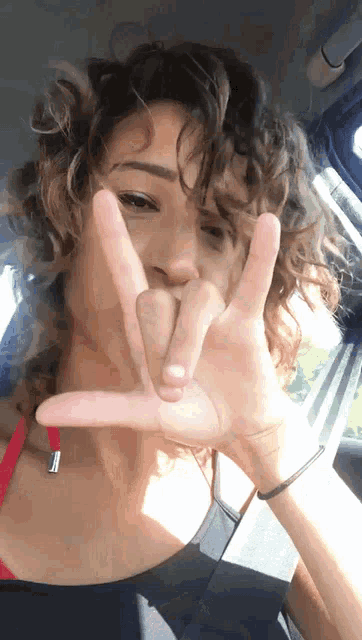 a woman with curly hair is making a i love you sign