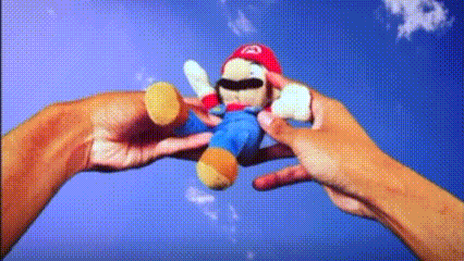 a person is holding a stuffed mario doll in their hands