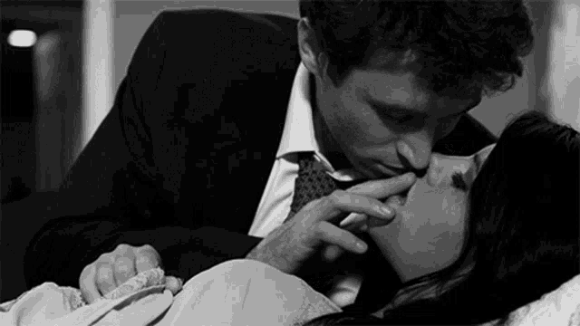 a man in a suit and tie kissing a woman on the lips