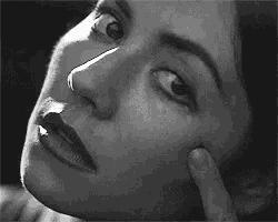 a close up of a woman 's face with her hand on her face .