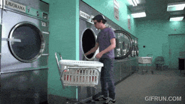 a man is putting a laundry basket into a laundromat