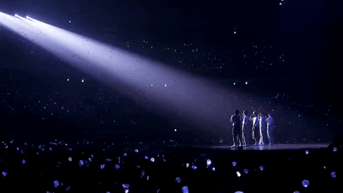 a group of people standing on a stage in front of a purple light .