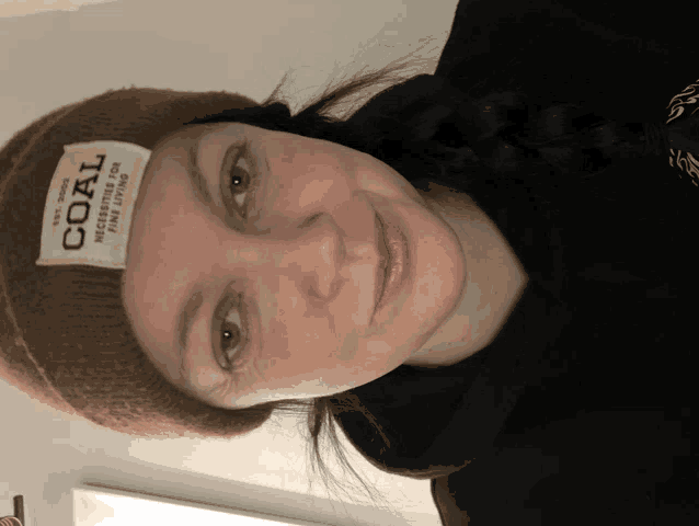 a woman wearing a brown beanie with a label that says coal