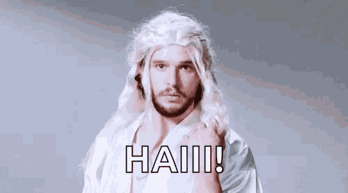 a man wearing a white wig and a white shirt is standing in front of a grey background .