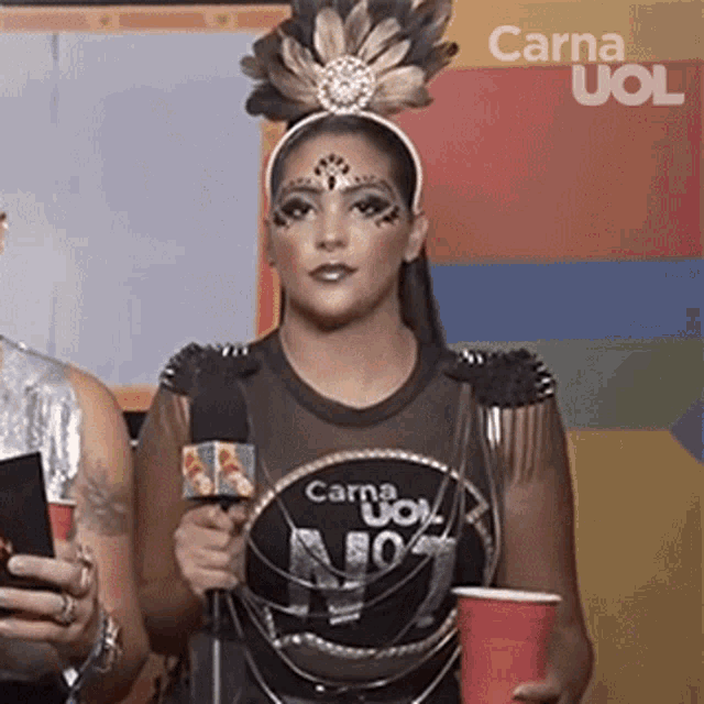 a woman wearing a black shirt that says carna uoi is holding a red cup