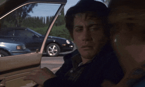 a man is sitting in a car with the door open