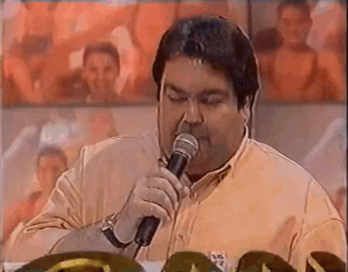 a man is singing into a microphone in front of a crowd of people .
