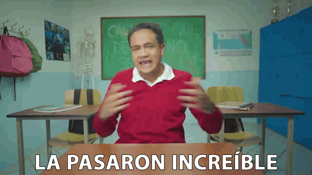 a man in a red sweater sits at a desk with the words la pasaron increible written on the desk
