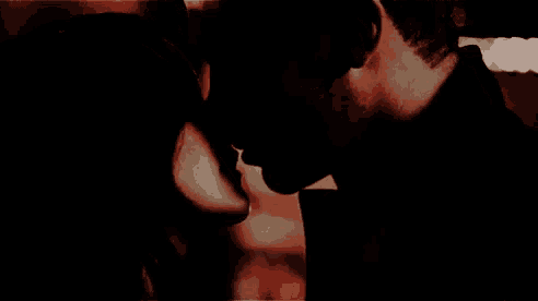a man and a woman are kissing in the dark in a dark room .