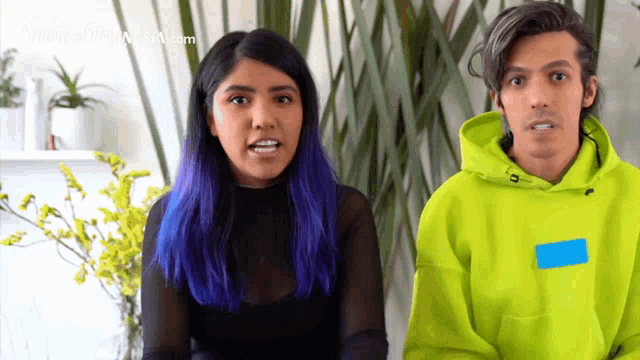 a woman with purple hair and a man wearing a neon green hoodie