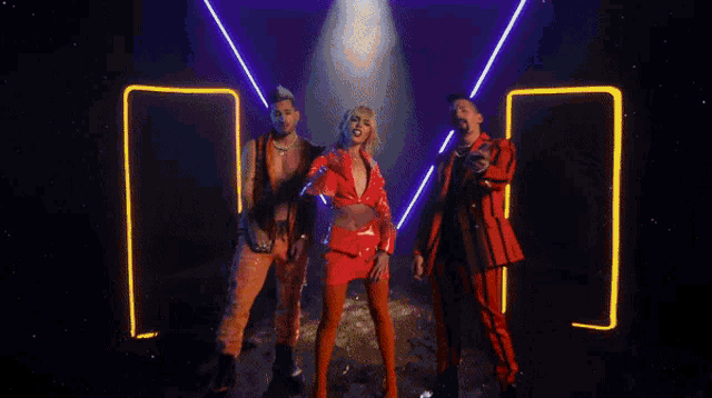 a woman in a red jacket is standing in front of a red curtain and giving the middle finger .