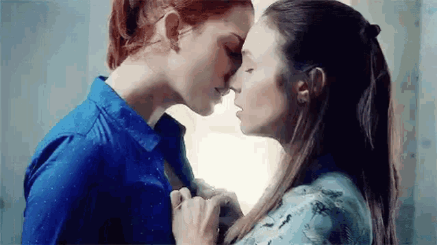 a couple of women are kissing each other on the forehead .
