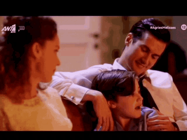 a man and a woman are hugging a young boy with the ant logo on the bottom