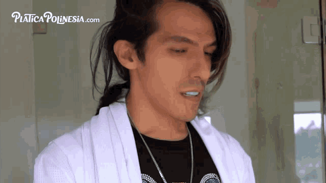 a man is wearing a white robe and a black shirt with the website platica polinesia.com written on the bottom right