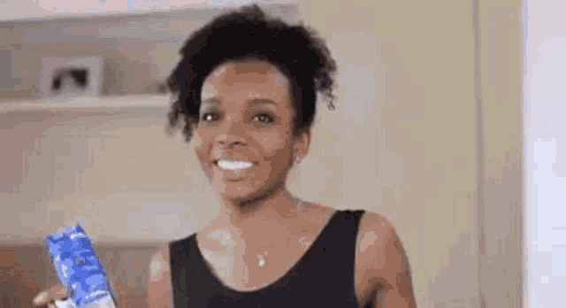 a woman is smiling while holding a package of ice cream .