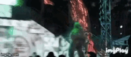 a man in a green shirt is dancing on a stage at a concert .