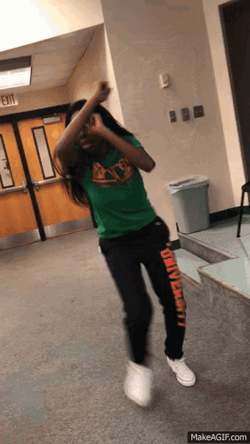 a girl in a green shirt and black pants with university written on them
