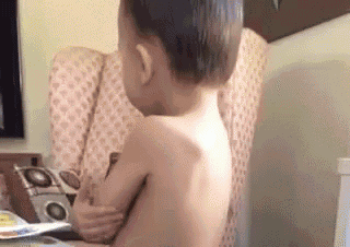 a shirtless little boy is sitting in a chair .