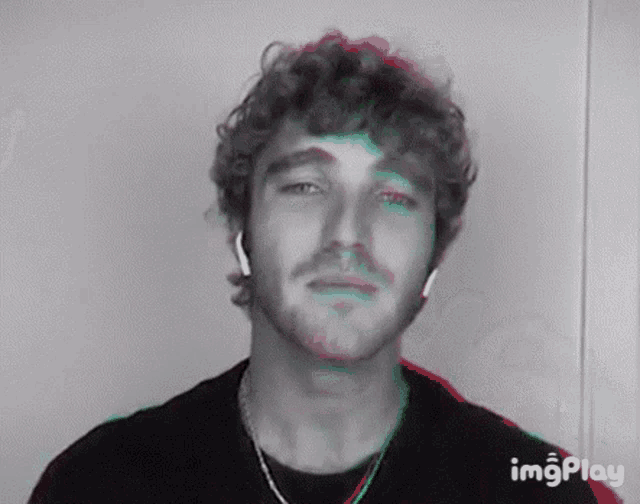 a man with curly hair and a beard is wearing headphones and a black shirt .
