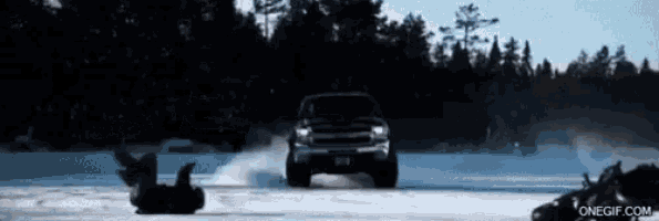 a truck is driving down a snowy road with a person on a sled