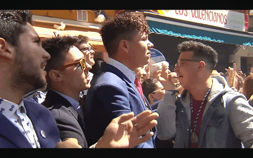 a group of men are standing in front of a sign that says los volencionarios