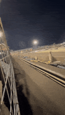 a view of a race track with a fence in the foreground