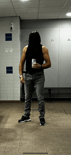 a man taking a picture of himself in a locker room with a sign that says no smoking