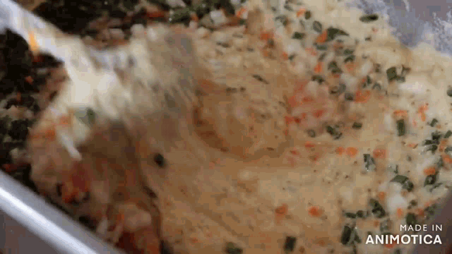 a close up of a person mixing a casserole dish with a spoon .