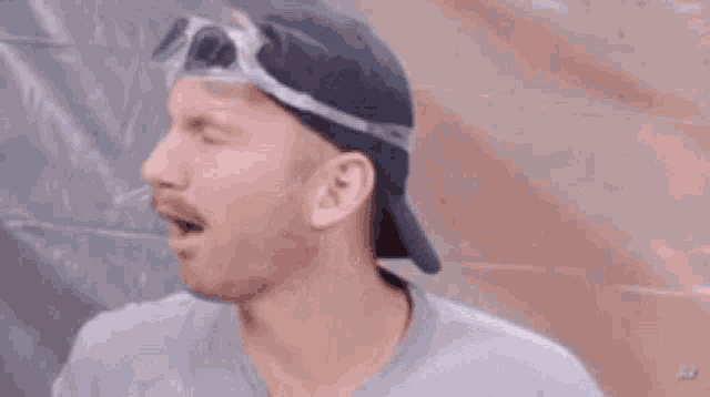 a man wearing a hat and goggles is making a face .