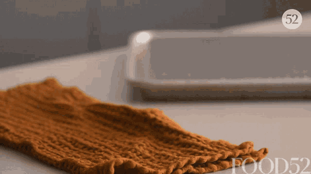 a knitted scarf is laying on a table next to a tray with the number 52 on it