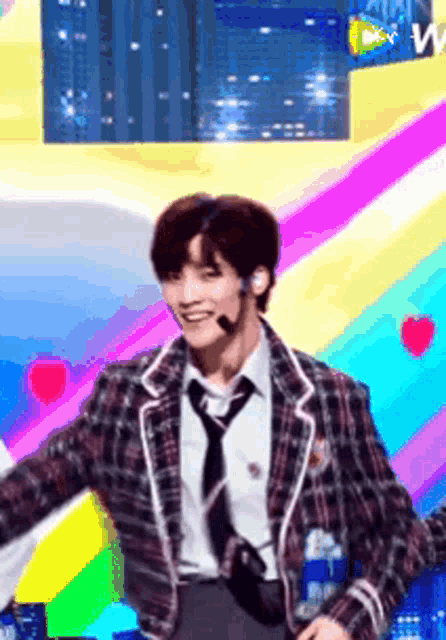 a man in a plaid jacket and tie is standing on a stage .