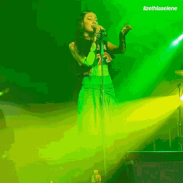 a woman singing into a microphone with the name lizethlaselena on the bottom right