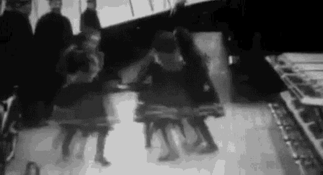 a black and white photo of a group of people dancing on a stage .