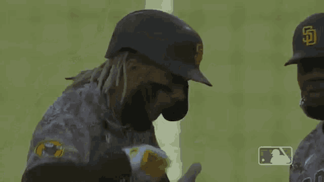 a baseball player with dreadlocks and a beard wearing a helmet is standing on a field .