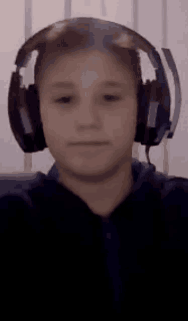 a boy wearing headphones is taking a selfie .
